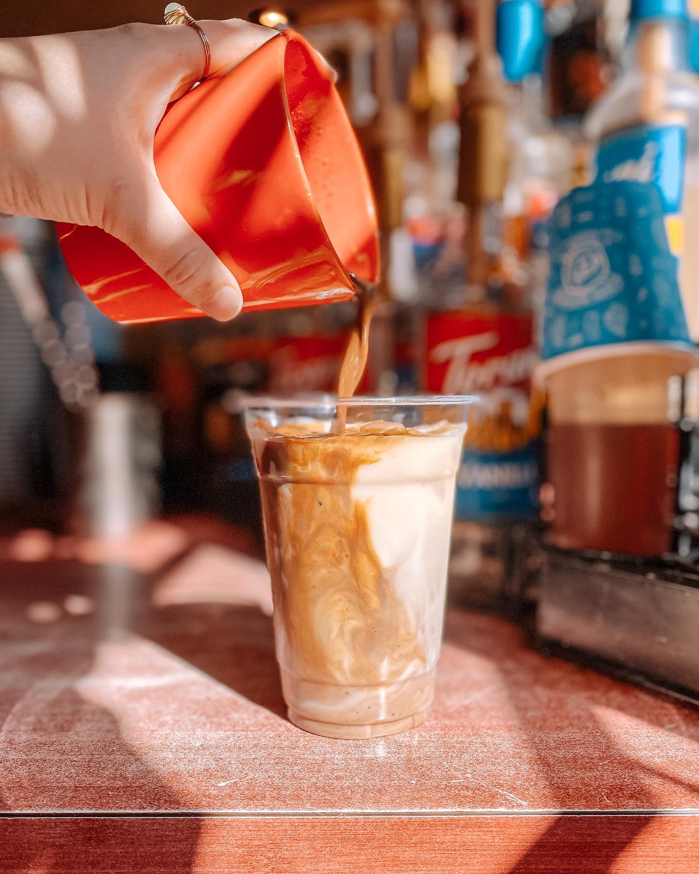 Barista pouring iced latte