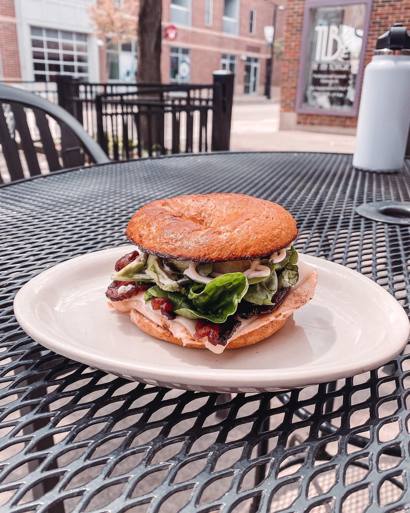 Turkey bacon avocado bagel sandwich on the patio