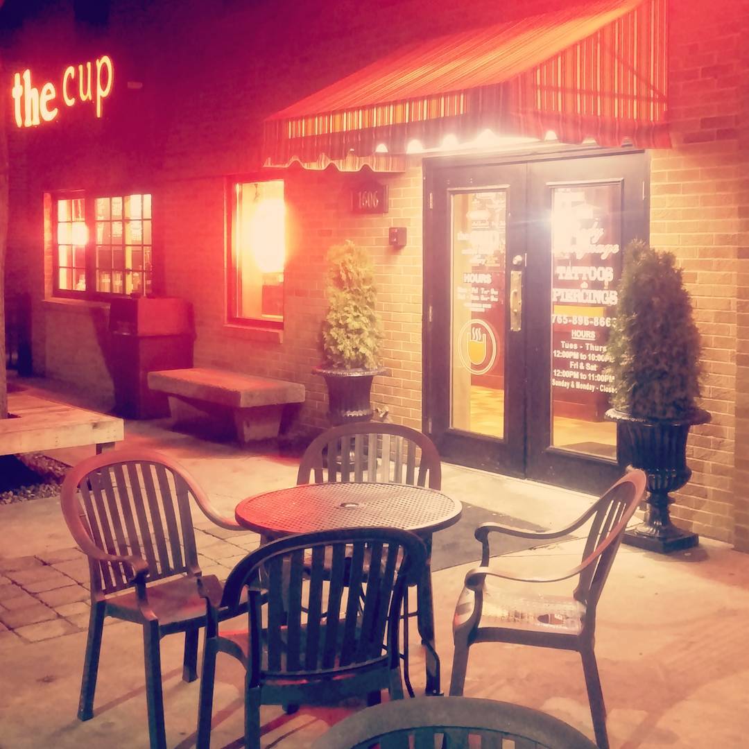 The Cup storefront at night with patio seating